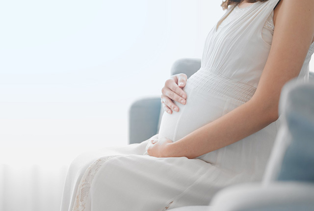 妊婦さんが椅子に座りお腹を触る様子
