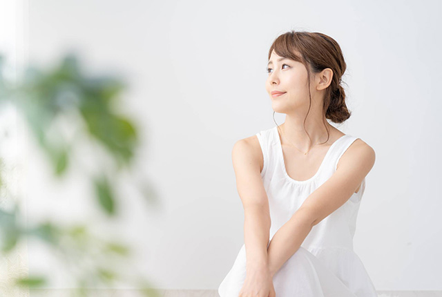 観葉植物がある部屋で外を見る若い女性